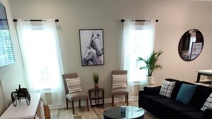 A modern living room with a black sofa, a round coffee table, and a ceiling fan. - Horse Ranch Getaway (Richlands)