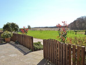 A wooden fence with a stone pathway leading to a grassy field.