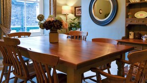 A dining area with a wooden table and chairs, a vase of flowers, a lamp, and a mirror on the wall. - 4 bedroom accommodation in Coniston (Coniston)