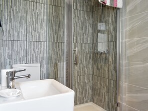Un bany modern amb dutxa, un lavabo i un vàter.