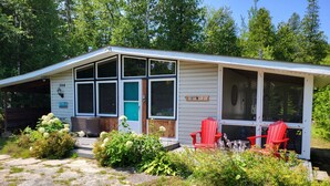 Ein kleines, eingeschossiges Haus mit einer überdachten Veranda, einer grünen Tür und der Hausnummer 504 an der Seite.