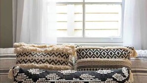 A bed with three decorative pillows in front of a window with blinds. - Uptown Glam - Best Amenities & Neighborhood (New Orleans)