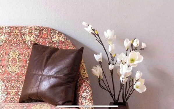 Un sofá con funda estampada de flores y un cojín de cuero marrón.