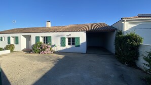 A two-story building with a tiled roof, a garage, and a gravel driveway.