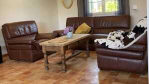A living room with brown leather sofas, a wooden coffee table, and a window with curtains.