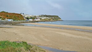 A beach with a stone wall and houses on a hill in the background. - 2 bedroom accommodation in Amlwch (Amlwch)