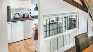 A kitchen with white cabinets, a red toaster, and a window with a metal grid.