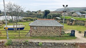 A stone building with a tiled roof, surrounded by picnic tables and a boat. - 1 bedroom accommodation in Mevagissey (Mevagissey)