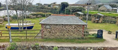 A stone building with a tiled roof, surrounded by picnic tables and a boat.