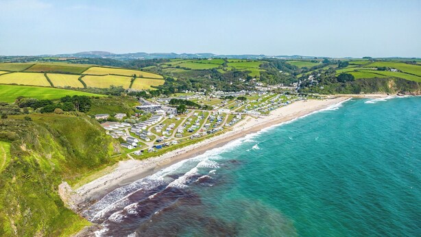 An aerial view of a coastal area with a beach, a caravan park, and surrounding green fields. - 1 bedroom accommodation in Mevagissey (Mevagissey)