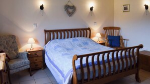 A bedroom with a wooden bed, two bedside tables, a chair, and wall-mounted lamps. - 2 bedroom accommodation in Easby Grange, near Great Ayton (Easby Grange, near Great Ayton)