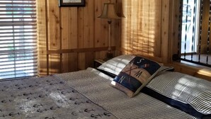 A wooden cabin room with a bed, a framed picture on the wall, and a window with blinds. - Lake Front Gated Property  Private Dock 
Book 3 Nights - Get 4th Night Free.  (Wills Point)