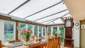A conservatory with a dining table set for six, surrounded by wooden chairs. - 5 bedroom accommodation in Ludham (Ludham)