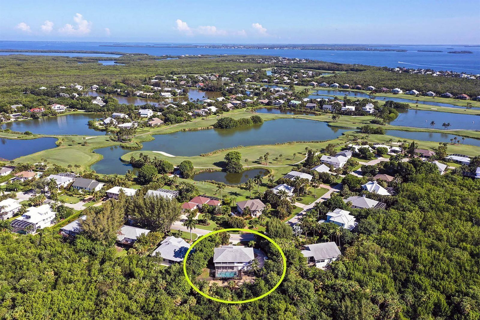 An aerial view of a residential area with houses, water bodies, and a golf course.