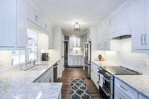 A modern kitchen with white cabinetry, granite countertops, a central island, and a chandelier. - My Sand Castle (Sanibel)