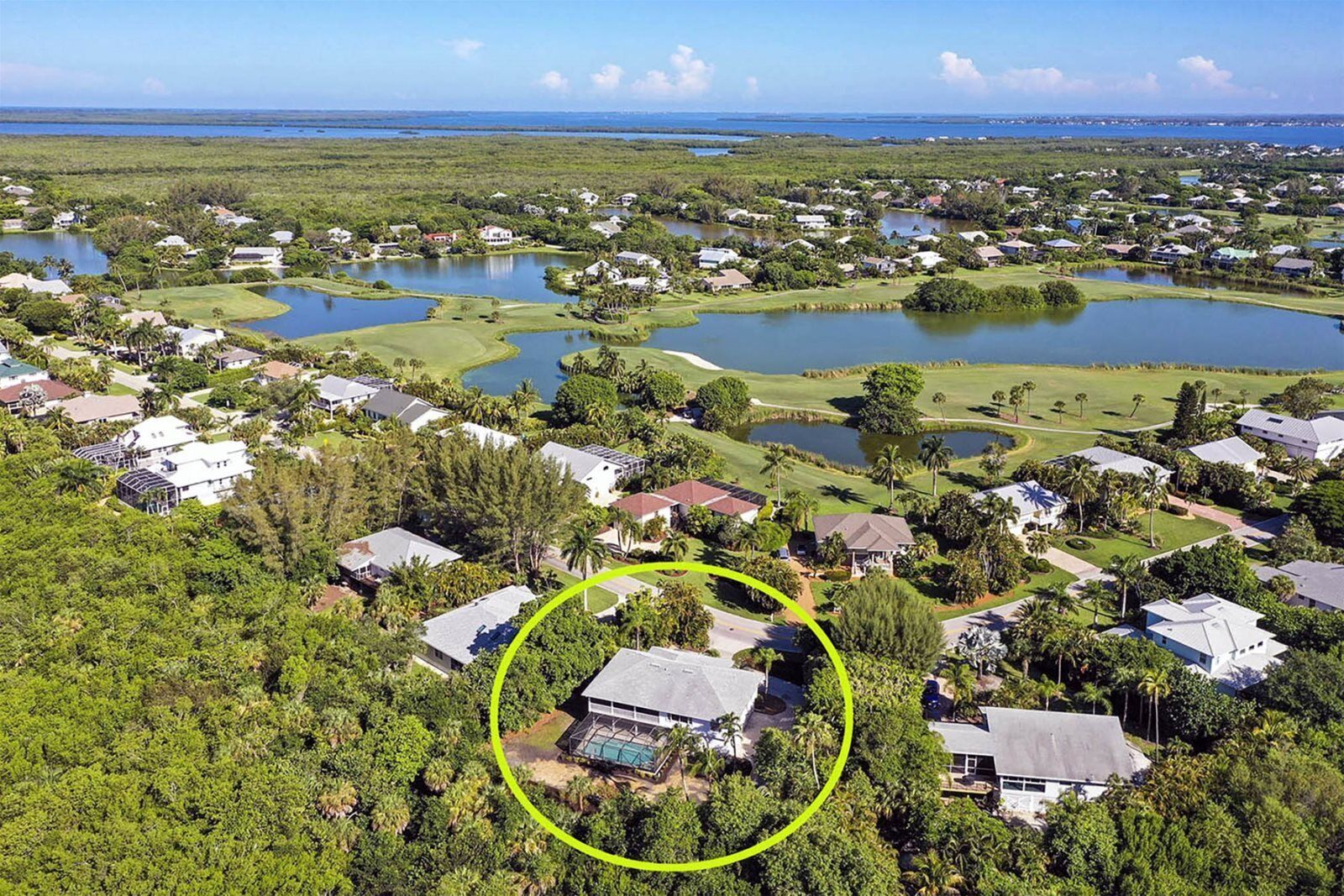An aerial view of a residential area with houses, a golf course, and multiple water bodies.