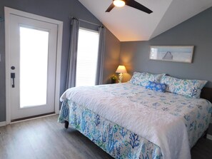 A bedroom with a bed, a ceiling fan, a window with curtains, and a wall-mounted lamp. - Ocean Lakes 308 | Fish off the deck, relax and enjoy the salt air breeze (Myrtle Beach)