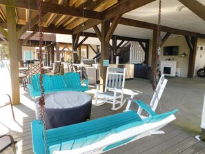 A covered outdoor area with wooden beams, a swing set, a grill, and a fireplace. - Ocean Lakes 308 | Fish off the deck, relax and enjoy the salt air breeze (Myrtle Beach)