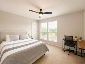 A bedroom with a bed, a desk, a chair, a ceiling fan, and a window. - Modern South Austin Home|King Bed • Gym • Patio • Sleeps 6- Ideal for long stays (Austin)