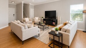 A modern living room with a sofa, armchairs, a coffee table, a TV, and a bookshelf. - Modern South Austin Home|King Bed • Gym • Patio • Sleeps 6- Ideal for long stays (Austin)