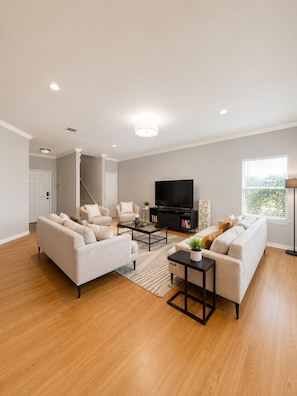 A modern living room with a sofa, armchairs, a coffee table, a TV, and a bookshelf. - Modern South Austin Home|King Bed • Gym • Patio • Sleeps 6- Ideal for long stays (Austin)