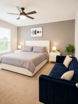 A bedroom with a bed, a nightstand, a desk, a chair, a ceiling fan, a window, and a wall-mounted artwork. - Modern South Austin Home|King Bed • Gym • Patio • Sleeps 6- Ideal for long stays (Austin)