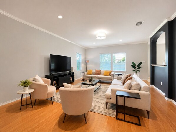 A modern living room with a flat-screen TV, two sofas, a coffee table, and a potted plant.