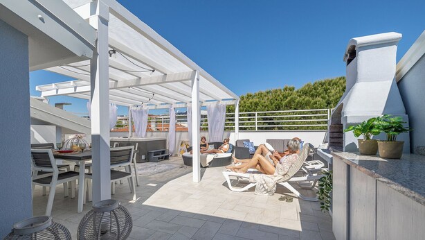 Une terrasse sur le toit avec des sièges extérieurs, un espace bar et une vue sur le paysage urbain.