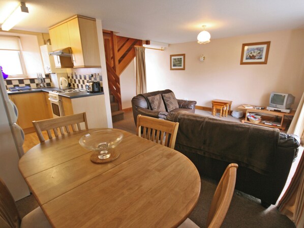 A compact living space with a dining table, a sofa, a TV, and a kitchenette.