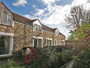 A stone house with a small garden and a narrow waterway.