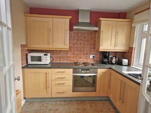 A kitchen with wooden cabinets, a microwave, a stove, and a coffee maker. - 1 bedroom accommodation in Bowden, Newton St Boswells (Bowden, Newton St Boswells)