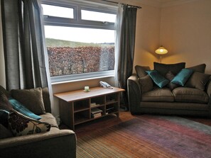 A living room with a sofa, a small table with a lamp, and a window with a view of a field. - 1 bedroom accommodation in Bowden, Newton St Boswells (Bowden, Newton St Boswells)