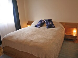 A neatly made bed with a beige blanket and two decorative pillows, a bedside table with a lamp, and a wooden headboard. - 1 bedroom accommodation in Bowden, Newton St Boswells (Bowden, Newton St Boswells)