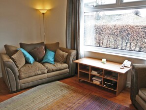 Een woonkamer met een bank, een salontafel en een boekenkast.