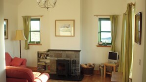 A cozy living room with a fireplace, a sofa, a television, and a bookshelf.