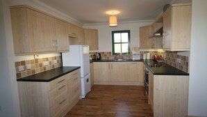 A kitchen with wooden cabinets, a refrigerator, a sink, and a window.