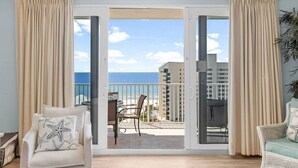 Ein Zimmer mit einer Schiebetür, die auf einen Balkon mit Blick auf das Meer und Gebäude führt.