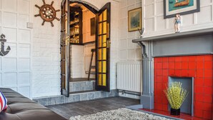 A room with a fireplace, a leather sofa, a ship's wheel, and a framed painting. - Situated in Whitby’s old town. (Whitby)