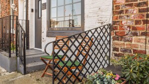 A brick building with a white facade, a window with a view, and a wooden chair outside. - Situated in Whitby’s old town. (Whitby)