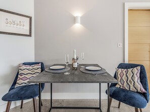 Een eettafel met twee stoelen, een fles champagne en twee wijnglazen.