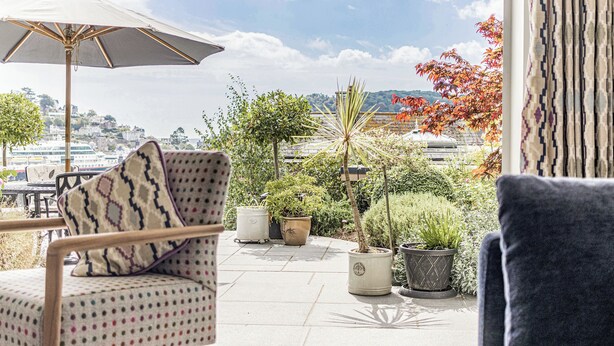 A patio with a chair, an umbrella, and potted plants. - 1 bedroom accommodation in 3 Coombe Close (3 Coombe Close)