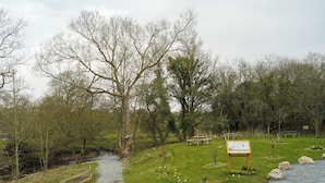Un parc avec un sentier de gravier, des tables de pique-nique et un panneau d’information.
