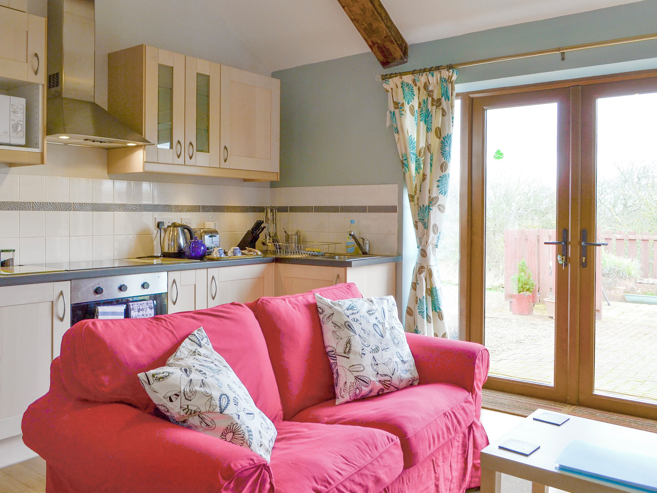 A kitchen with a pink sofa, a dining table with papers, and a view of the outside.