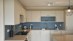 A modern kitchen with white cabinets, a blue backsplash, and a stainless steel sink.