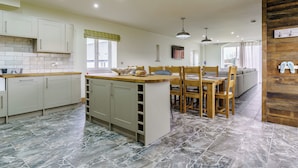 Una cocina moderna con armarios blancos, una isla de madera y un comedor con sillas y una mesa.