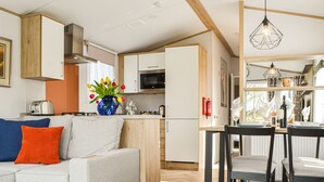 Une cuisine moderne avec des meubles blancs, un four à micro-ondes et un grille-pain. On y trouve également un coin repas avec une table et des chaises.