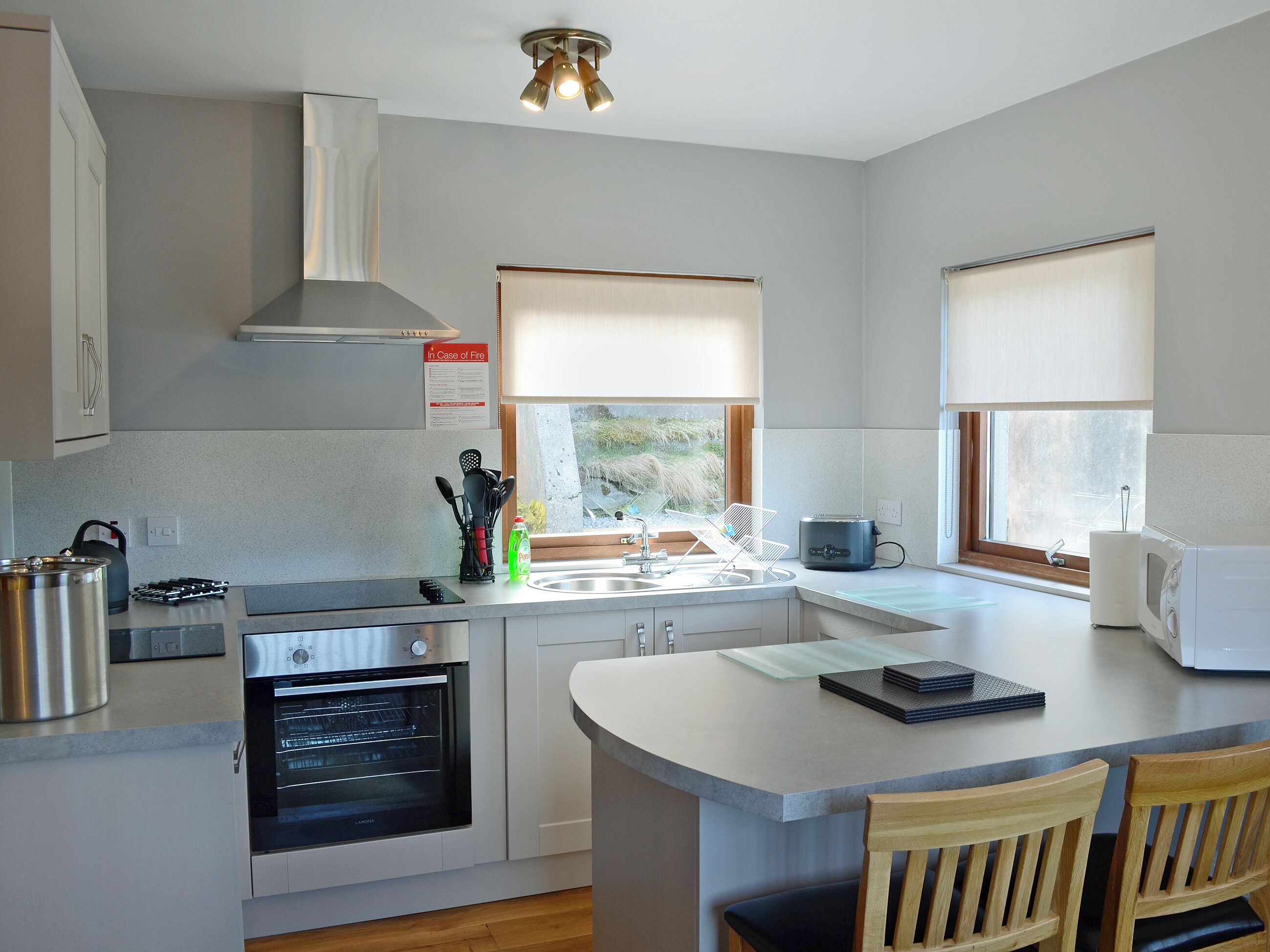 A modern kitchen with a built-in oven, a kettle, and a microwave.