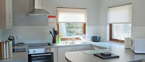 Una cocina moderna con horno empotrado, hervidor y microondas.