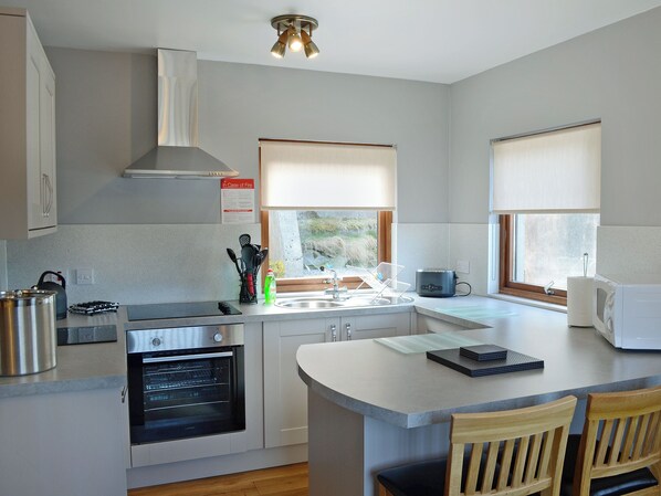 A modern kitchen with a built-in oven, a kettle, and a microwave.