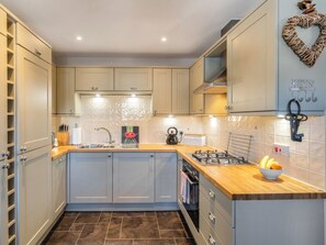 Una cucina moderna con mobili chiari, un piano di lavoro in legno, un piano cottura a gas e una decorazione a forma di cuore sul muro.